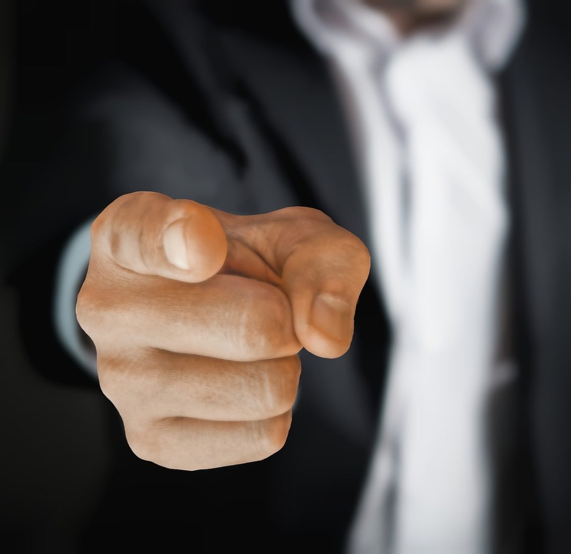 This is a picture of a hand pointing at you from a blurred out torso in a suit.