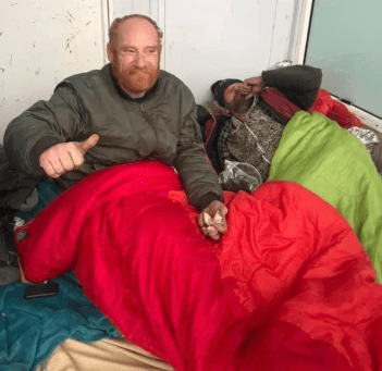Photo of 2 homeless men, one has his thumb up after receiving a care package.